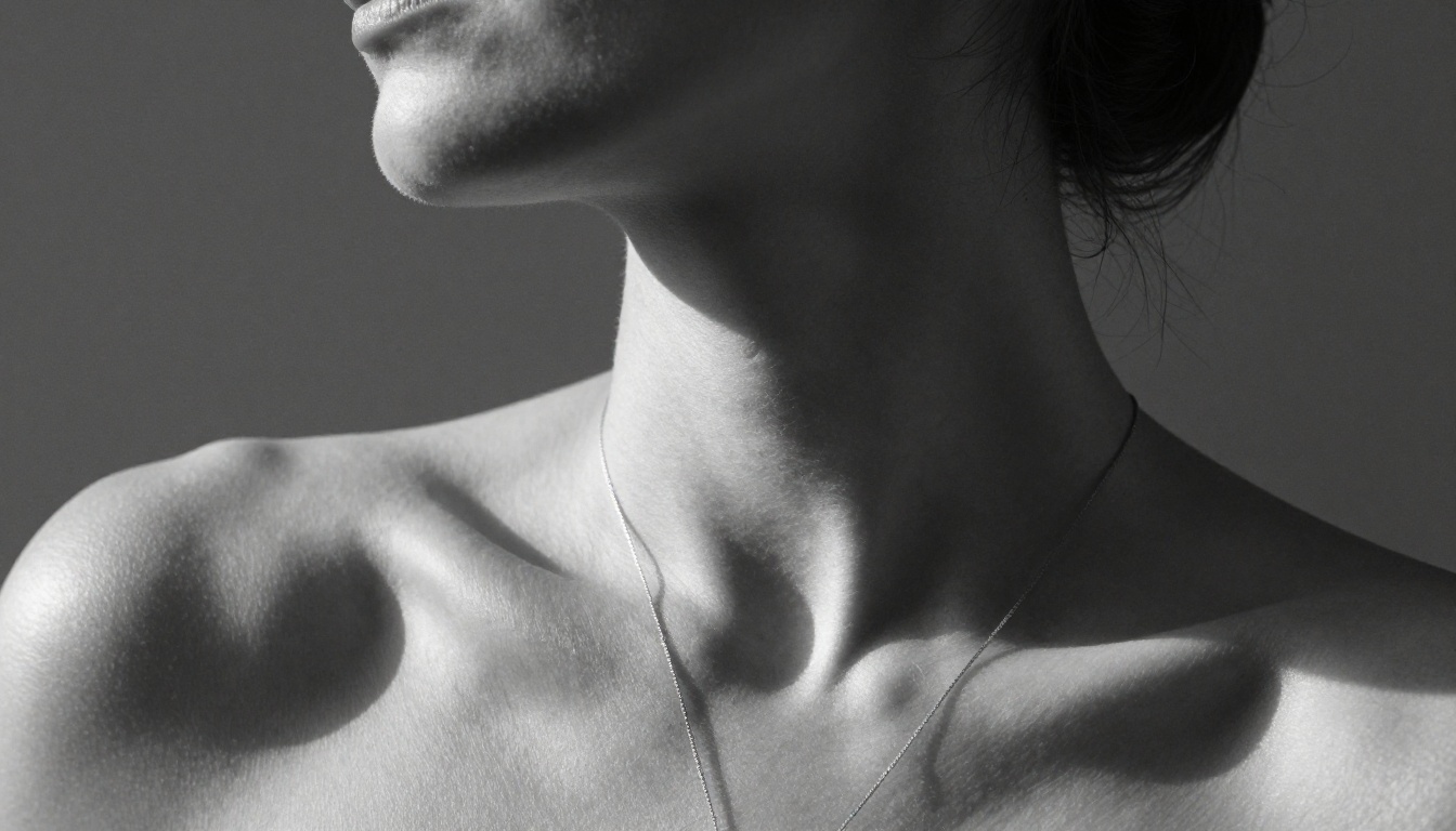Artistic black and white portrait of a woman's shoulder and neck in dramatic studio lighting